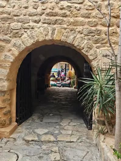 Passage voûté en pierre à Hammamet, ouvrant sur une ruelle ombragée